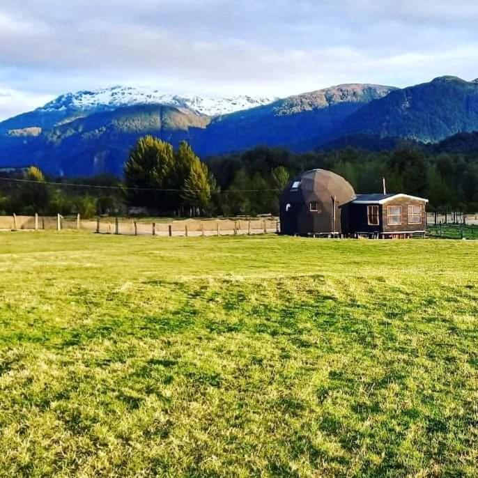 a barn in a field with mountains in the background at Oceana Suites Coyhaique in Puerto Dunn