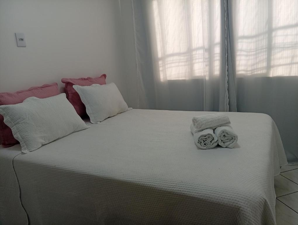ein weißes Bett mit zwei Handtüchern darauf in der Unterkunft Executivo central 101 in Ipatinga