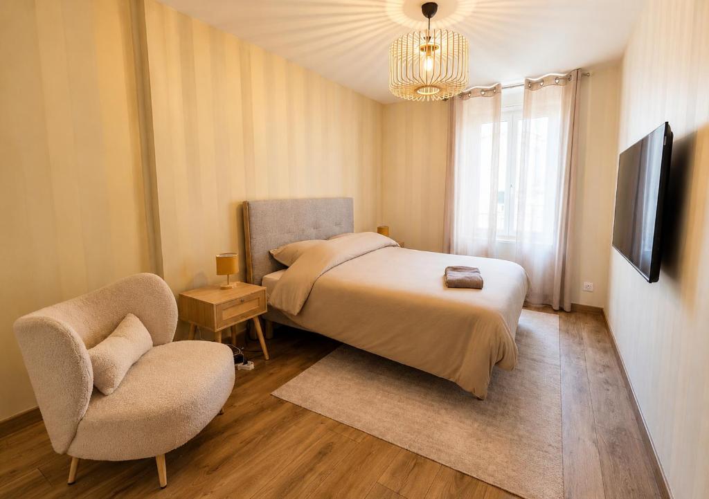 a bedroom with a bed and a chair and a television at L'Escale Strasbourgeoise climatisée in Strasbourg