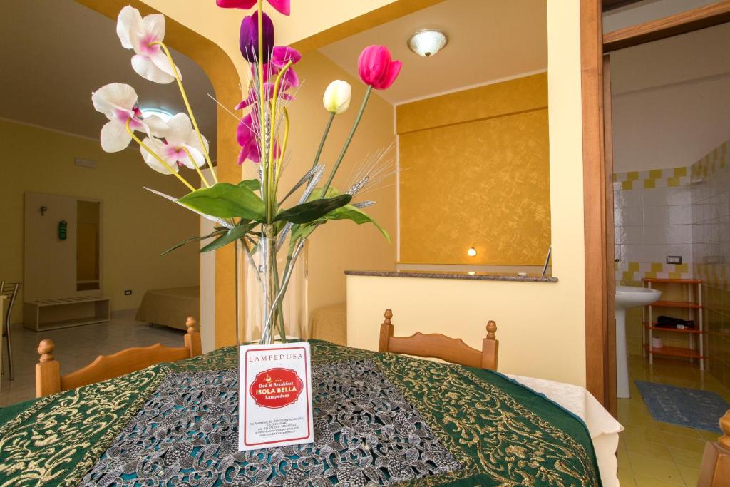 a vase of flowers sitting on top of a bed at Bed & Breakfast Isola Bella Lampedusa in Lampedusa