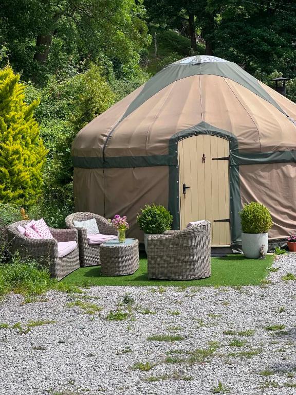 a tent with wicker chairs and chairs in a yard at Thistlebank Yurt in Llangollen