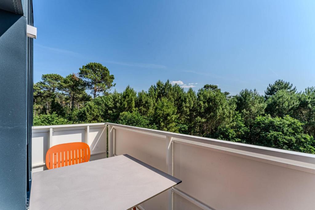 a table and a chair on a balcony with trees at Apartment for 5 with a forest view in La Teste-de-Buch