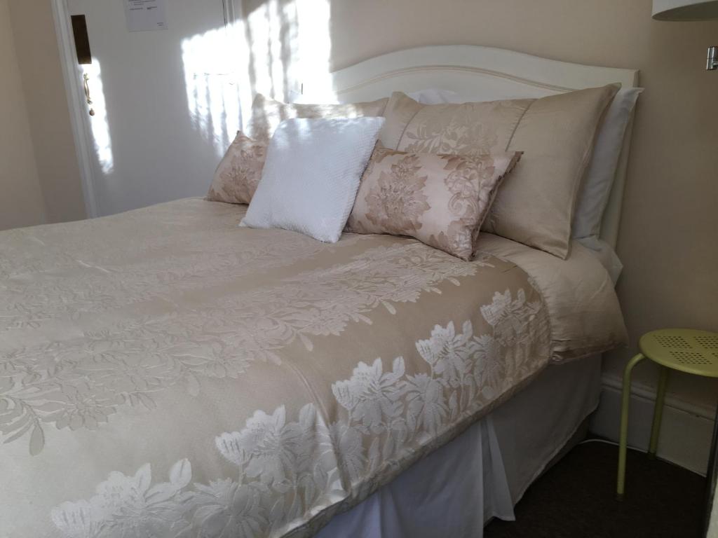 a white bed with pillows on top of it at CARIS Guest House in Southend-on-Sea