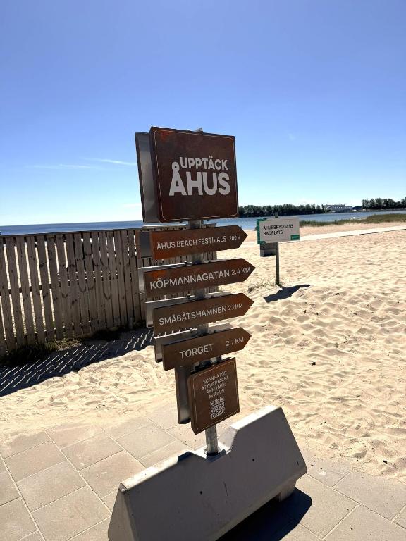 a sign on the beach with distances to different destinations at ÅhusBrygga Apartment Hotel in Åhus