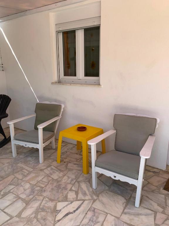 two chairs and a yellow table and a window at Quarto privado na natureza in Fernao Ferro