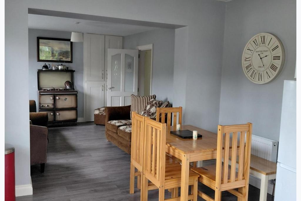 a living room with a table and a clock on the wall at Cottage - Sleeps 6 - Parking in Letterkenny