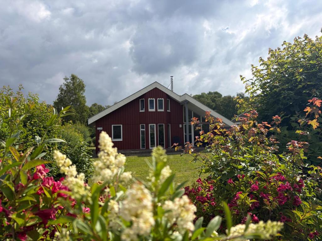 a red barn in the middle of a yard with flowers at Wildgans 10 in Rechlin