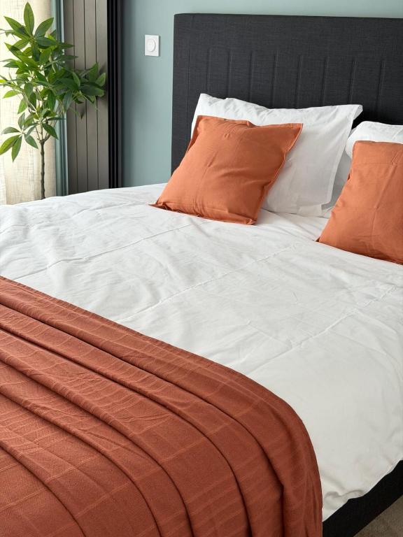 a bed with orange and white sheets and pillows at Suite indépendante proche Bordeaux in Rions