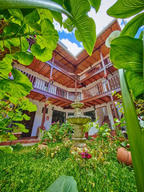 a garden in front of a house with a fountain at Hostal Catequil in Cajamarca
