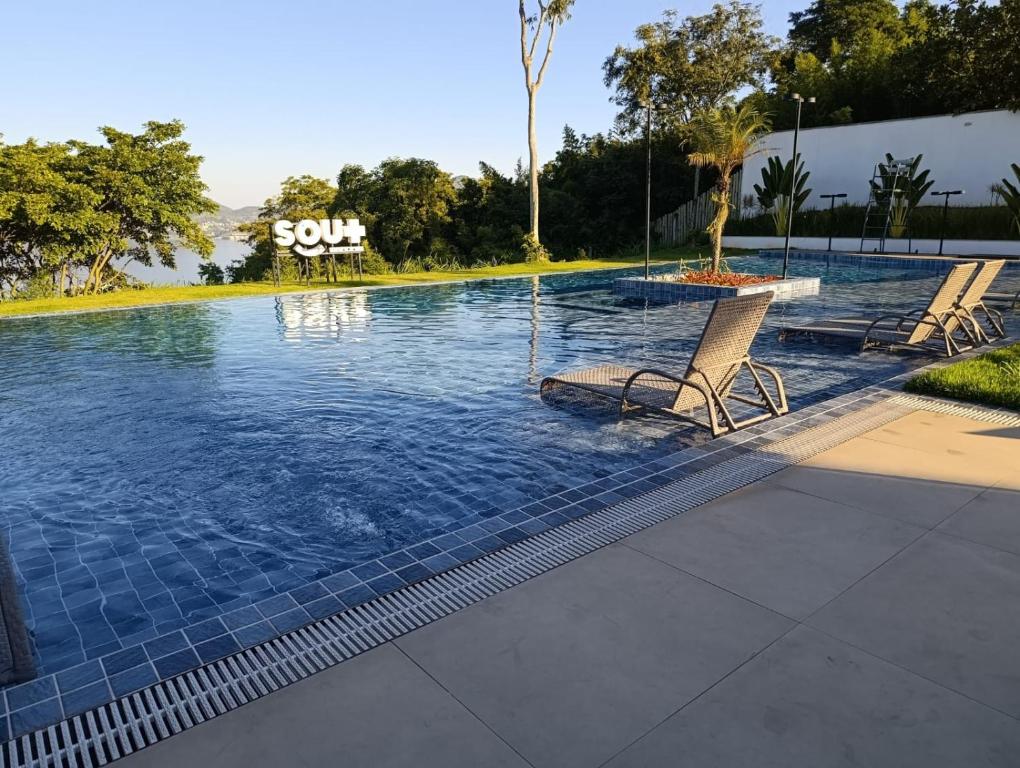a swimming pool with two chairs in the water at nityloft com piscina e academia em Icaraí in Niterói
