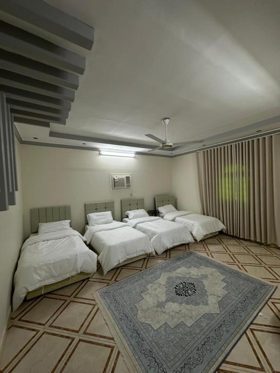 a room with four beds and a rug on the floor at شقة واسعة بحي الدوحة لـ 10 أشخاص 6دقائق للبحر in Yanbu