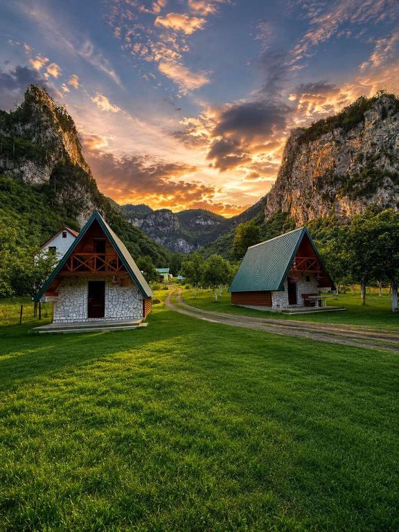 two barns in a field with mountains in the background at Guesthouse Stanisic in Dobrilovina