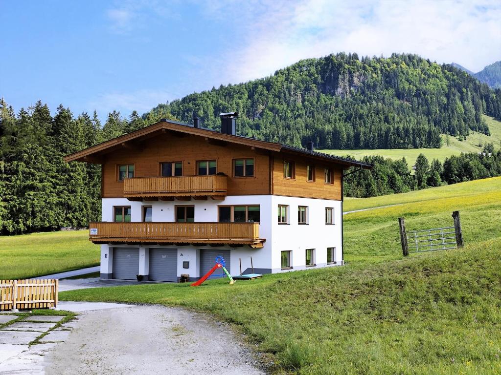 a house in a field next to a road at Ferienwohnung Lacken in Fieberbrunn
