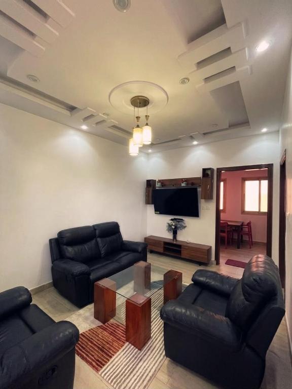 a living room with black leather furniture and a flat screen tv at Hotel Résidence Awa Plazza 2 in Dakar