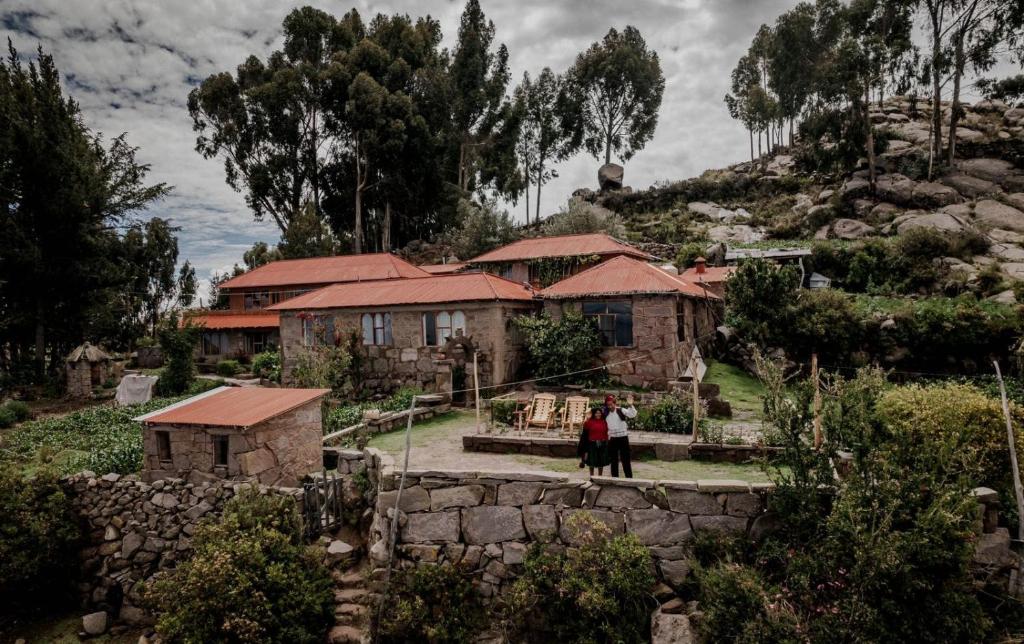 a group of people standing in front of a house at TAQUILE LODGE Perú in Huillanopampa
