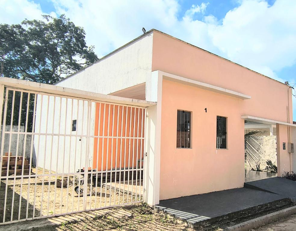 a pink and white building with a gate at Casa Inteira com Garagem, no Goiabal até 3 hospedes in Macapá