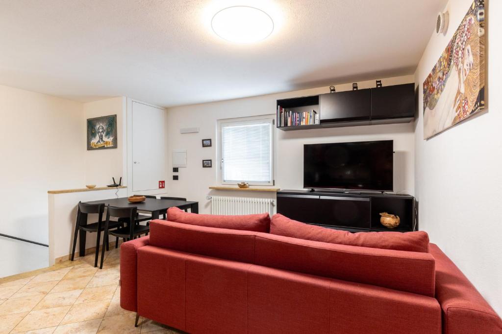 a living room with a red couch and a table at Aosta Centre Apartments - Santo Stefano in Aosta