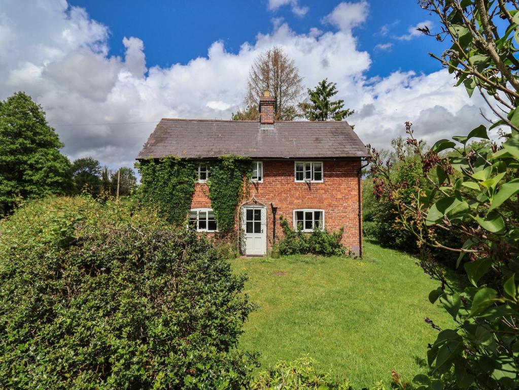 an old brick house with ivy growing on it at Wolvesacre Mill Cottage in Whitchurch