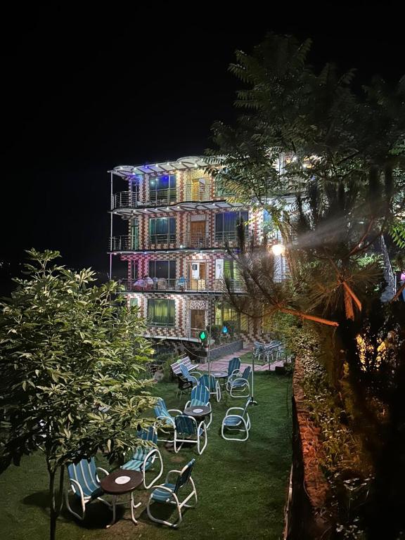 a group of chairs in front of a building at night at Bhurban Family Apartments in Murree