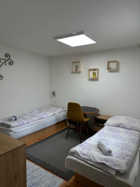 a room with two beds and a table and a chair at Apartmán Gál 1 in Kvačany
