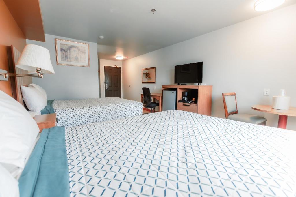 a hotel room with two beds and a flat screen tv at Bay City Inn in Bellingham