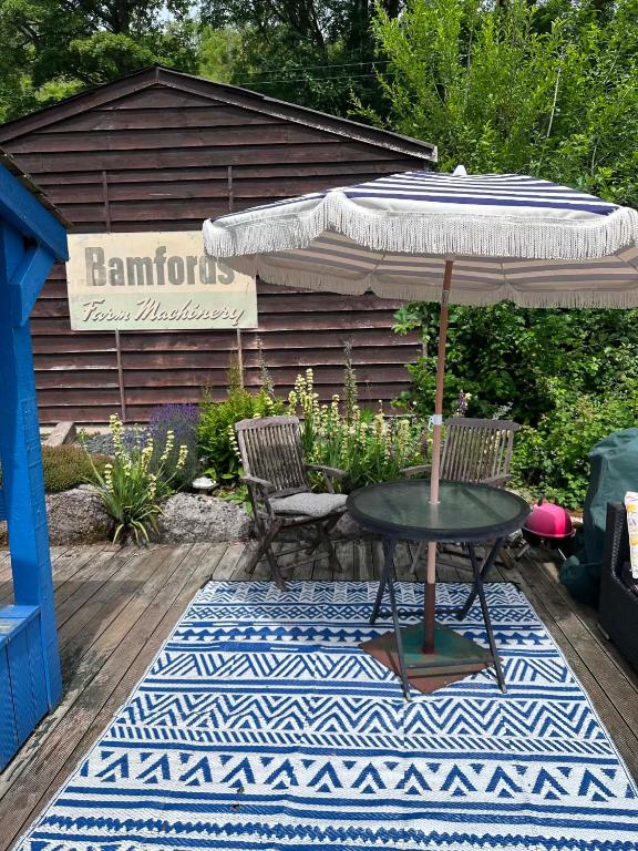 a table with an umbrella and two chairs on a rug at Sunbank Yurt in Llangollen