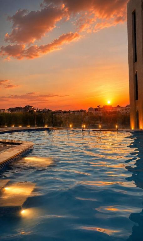 a large swimming pool with the sunset in the background at chalet in saint remon in Al ‘Ayn