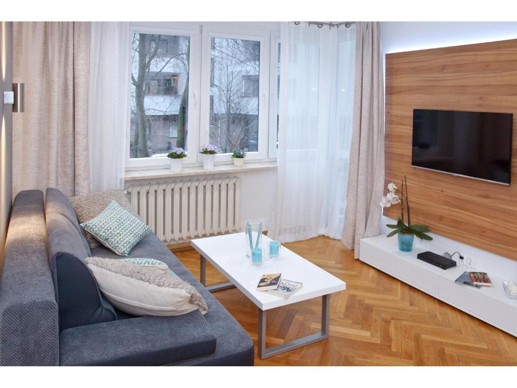 een woonkamer met een bank en een tafel bij Srebrna Warsaw Apartment in Warschau