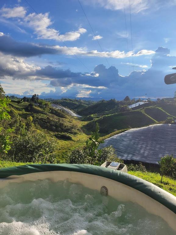 a hot tub with a view of a body of water at Cozy Cabin in avocado farm in Marinilla