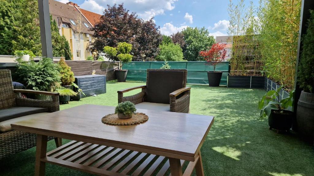 a patio with a table and chairs on the grass at Green Terrace Residence in Zalaegerszeg
