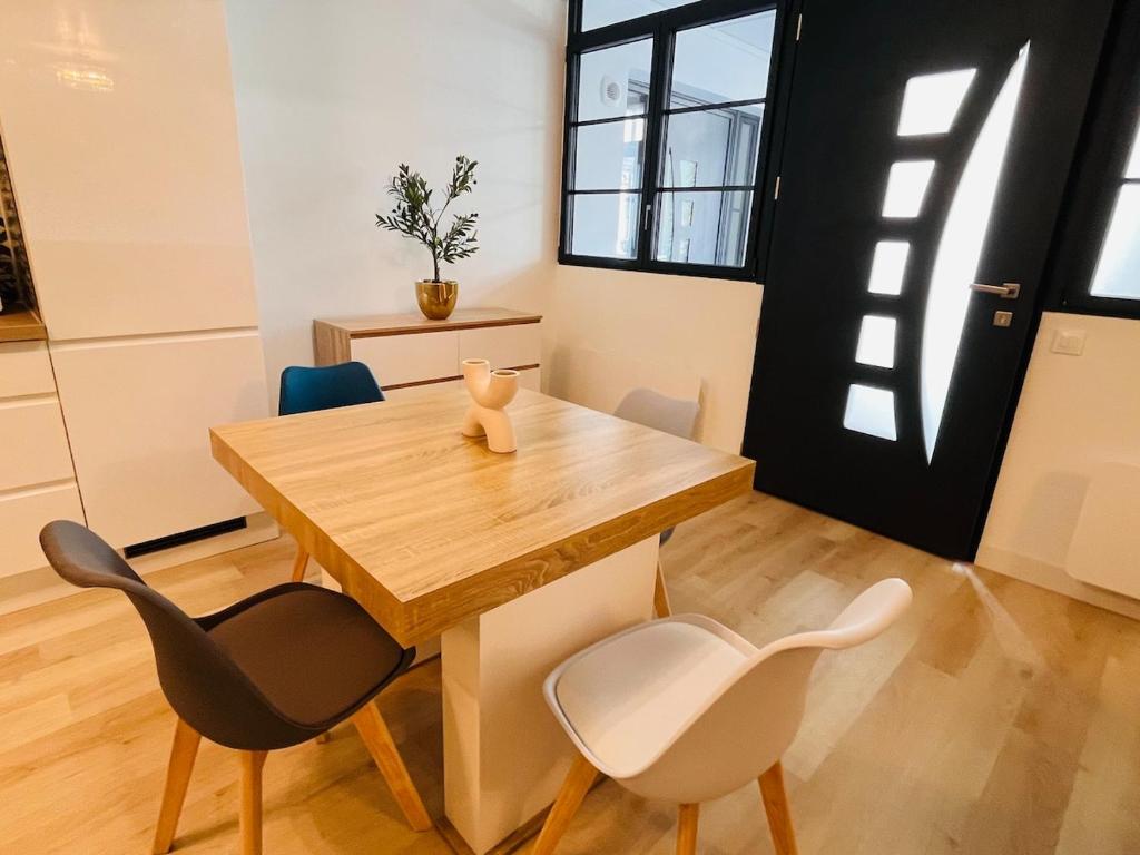 a dining room with a wooden table and chairs at Le Faubourg St Martin Gold&Green in Senlis