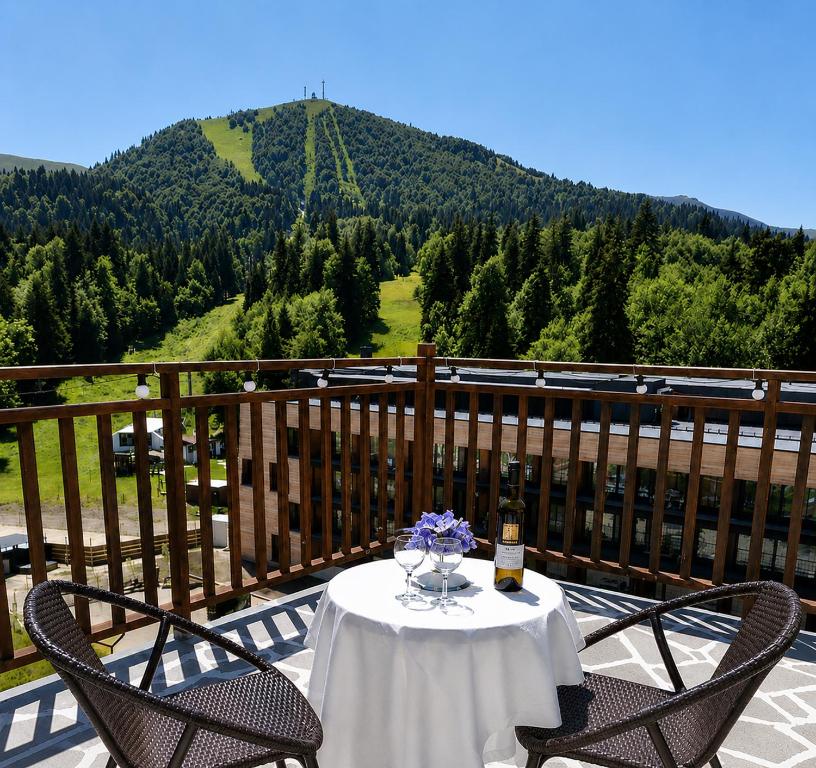 a table and two chairs on a balcony with a mountain at BM Plaza in Bakuriani