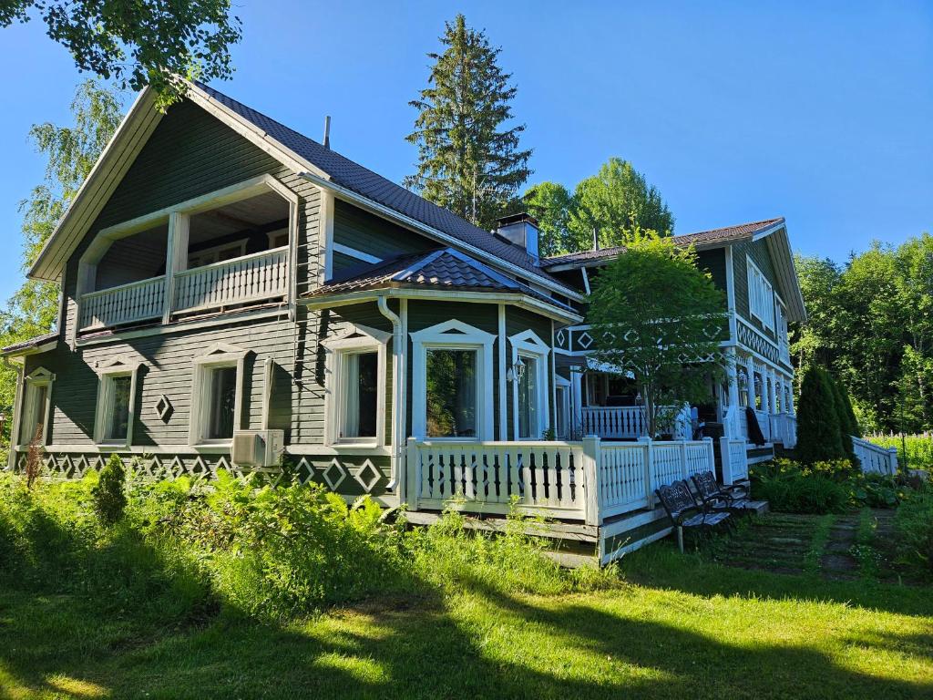 a large house with a porch on a lawn at Villa Gargano in Pieksämäki