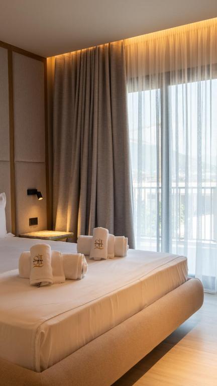 a large bed with white pillows in a room with a window at South Inn Marina Hotel in Vlorë