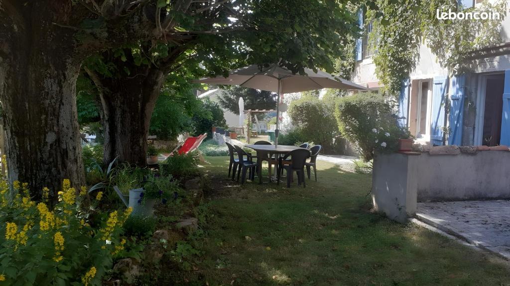 a table and chairs under an umbrella in a yard at Le Gite Des Peyreyres in Lespéron