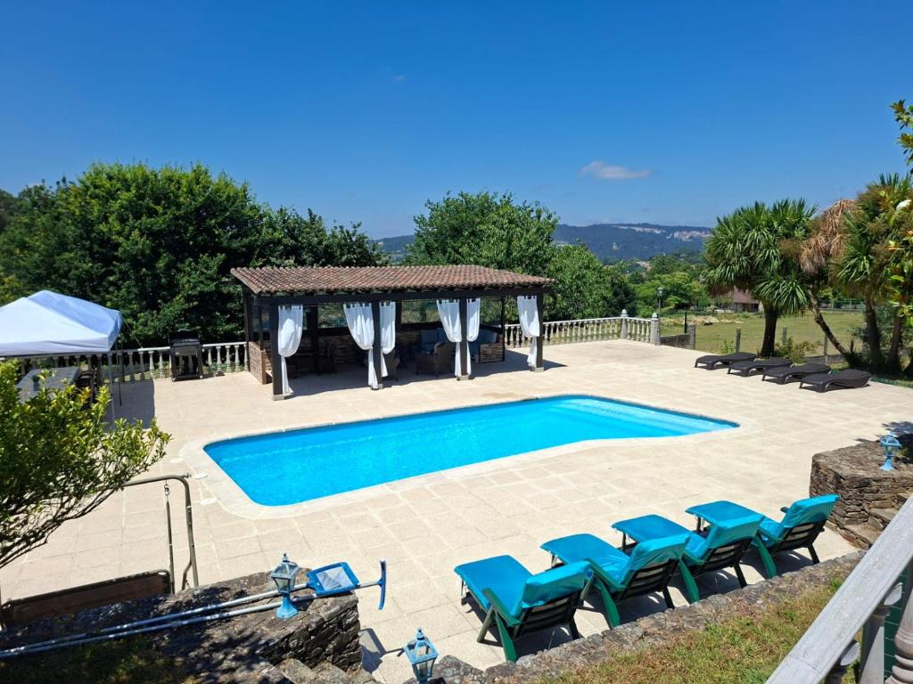 a swimming pool with chairs and a gazebo at As Seis Chemineas in San Xulián de Sales