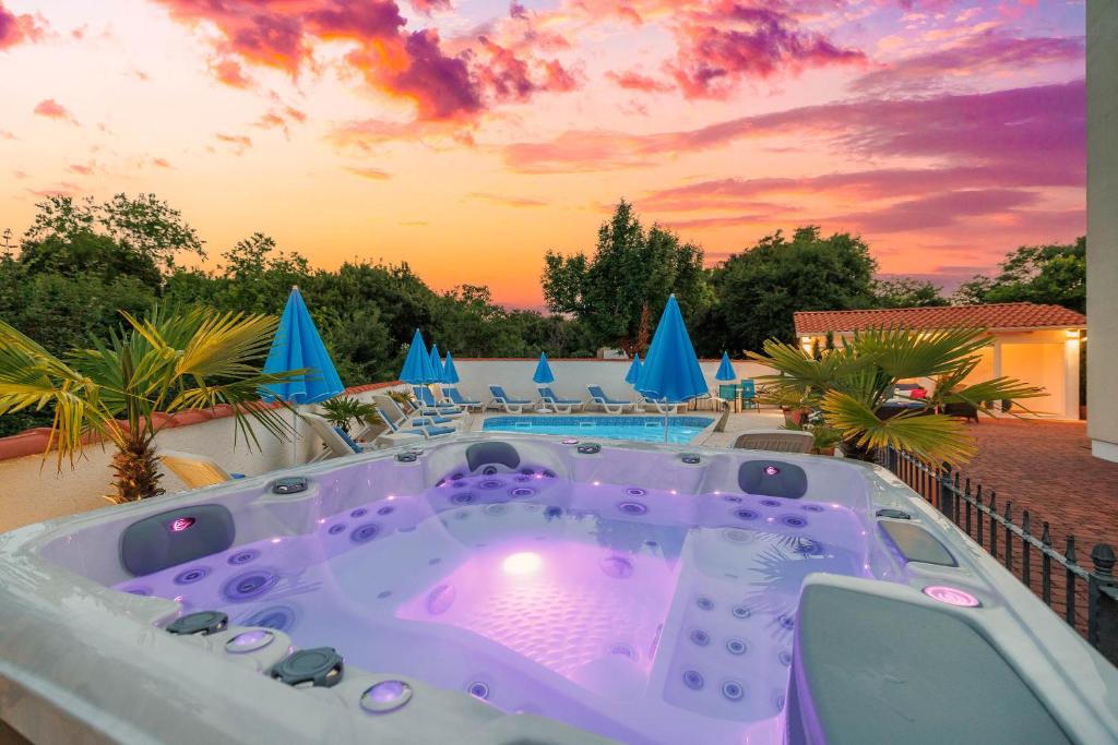 a jacuzzi tub on a patio with a sunset at Palmer Residence Krk in Dobrinj