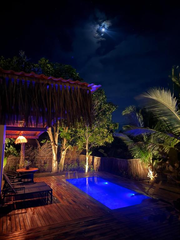 a swimming pool at night with the moon in the background at Corumbau Bangalôs in Corumbau