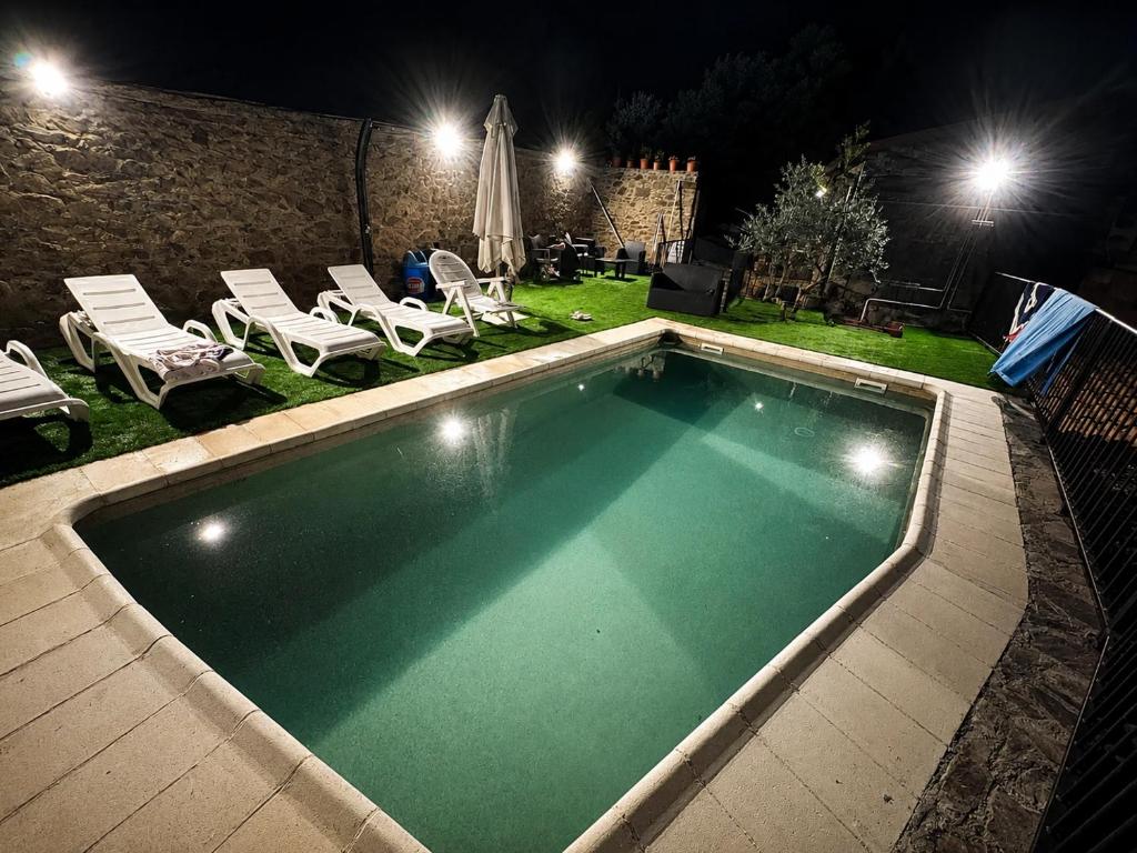 a swimming pool at night with chairs and umbrellas at Las Casitas Del Bodegon in El Gasco