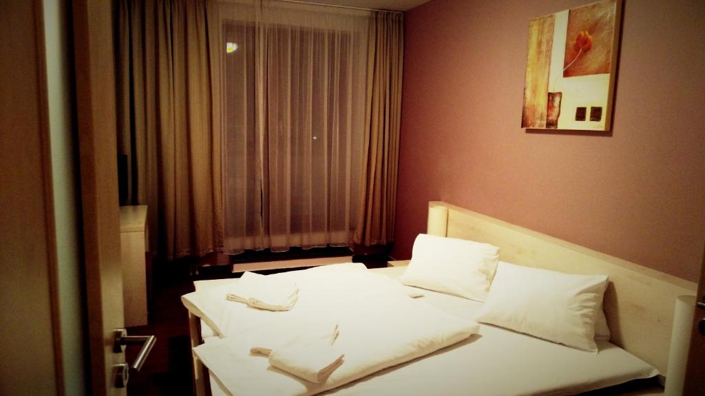 - une chambre avec 2 lits blancs et une fenêtre dans l'établissement Apartmán Hory, à Štrbské Pleso