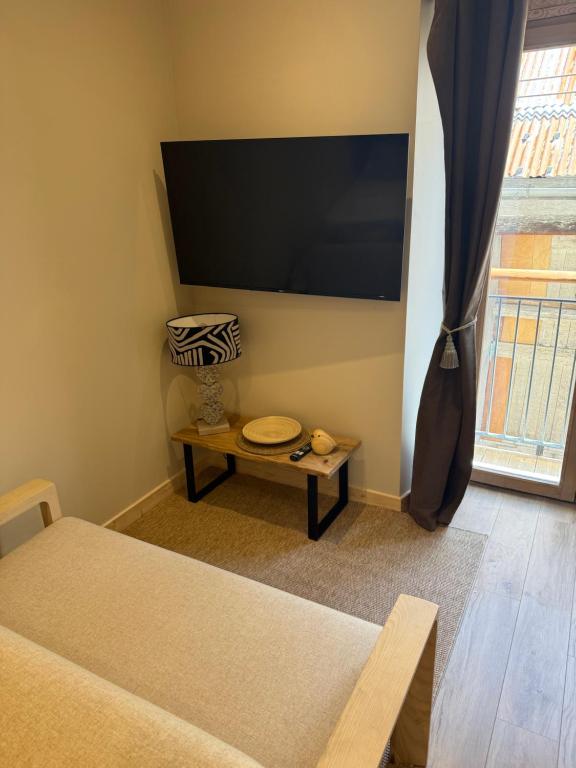 a living room with a tv and a table at Le Col Getaway Virage 5 in Le Bourg-dʼOisans