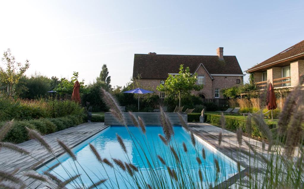 a swimming pool in front of a house at Country House Duinhof in De Haan