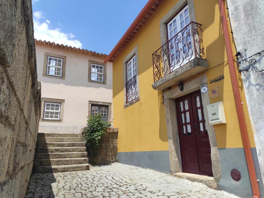 a yellow and blue building with a red door at Casa do Lagar in Almeida