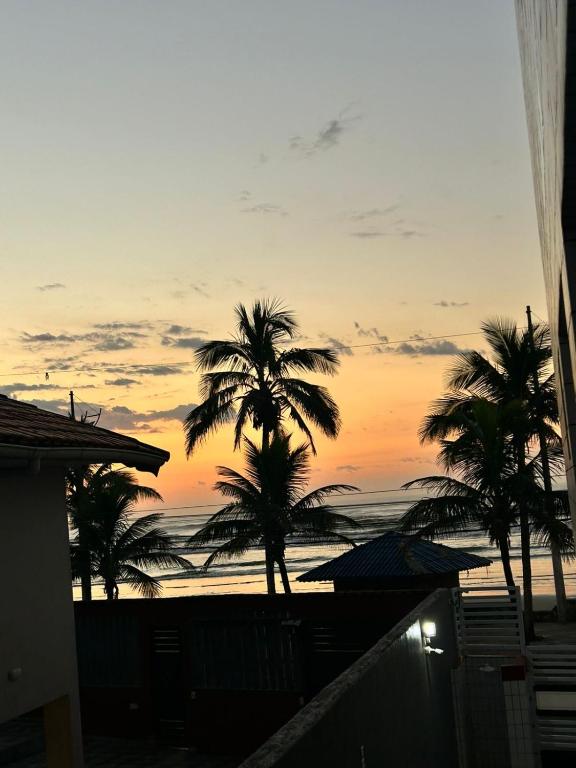 a sunset from the balcony of a house with palm trees at Apto Sol Nascente in Mongaguá