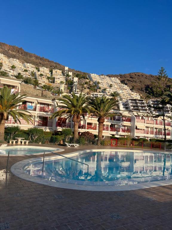a large swimming pool with palm trees and buildings at Cura Marina in Playa del Cura