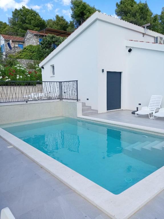 a swimming pool in front of a white house at Villa Mala Smišna Poolside Paradise by the Sea in Maslinica