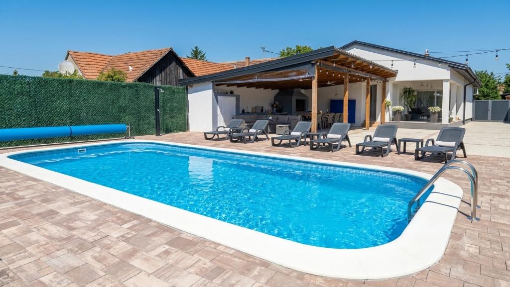 a swimming pool with chairs and a table and a house at Kuća za odmor Terra Marta in Đakovo