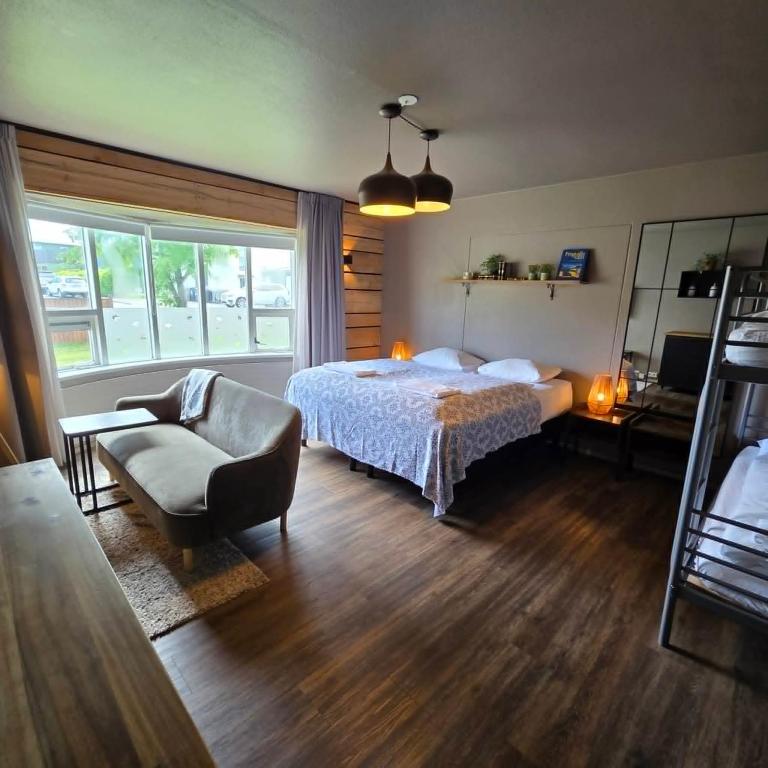 a bedroom with a bed and a couch and a chair at Akureyri Hostel in Akureyri