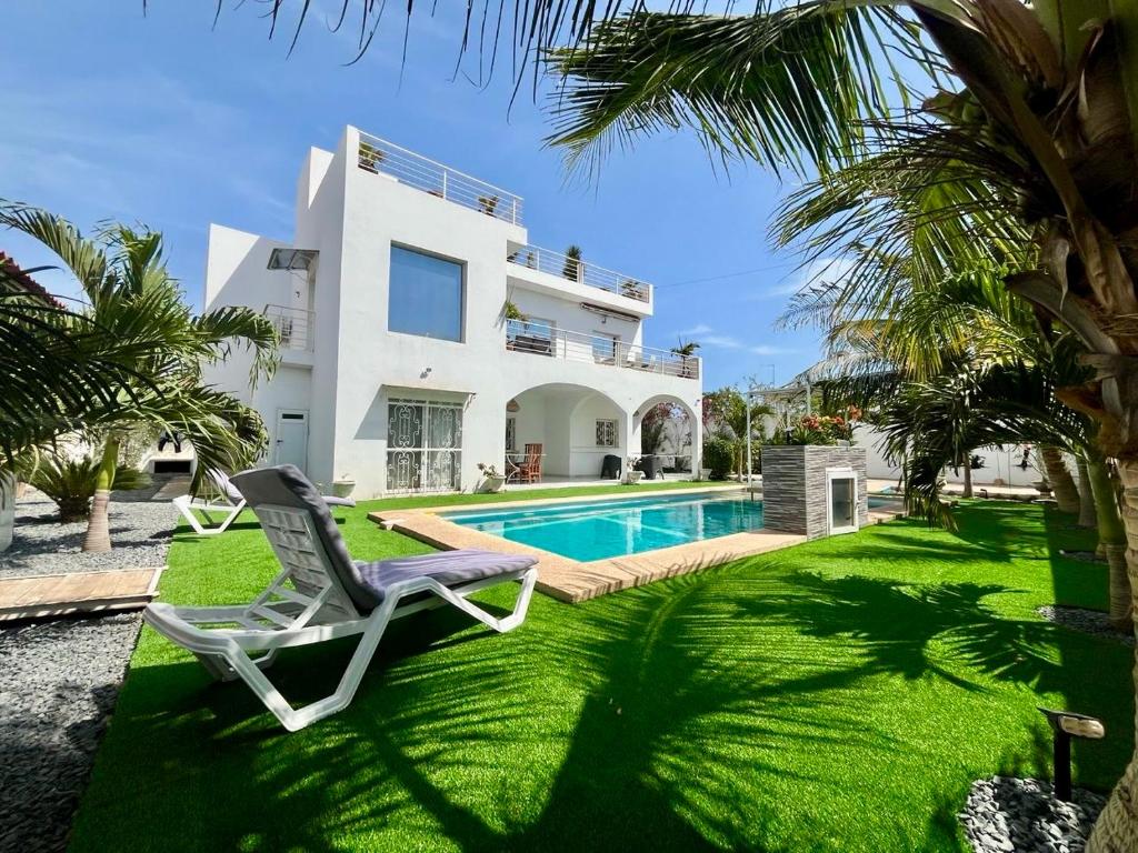 a villa with a swimming pool and a chair at KEUR MATY Charmante et Moderne Villa 5 chambres, 5 salles de bains à Warang in Ouoran
