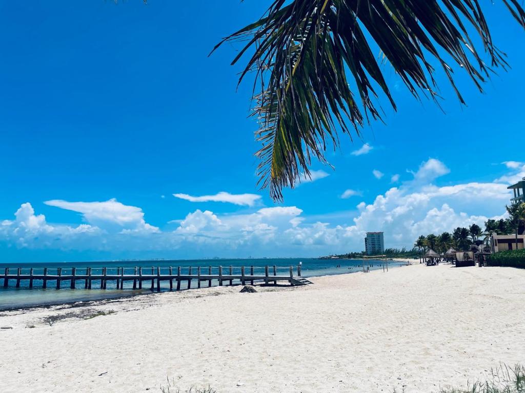 a sandy beach with a pier in the distance at Economic Apartments & Rooms next to the beach in Cancún
